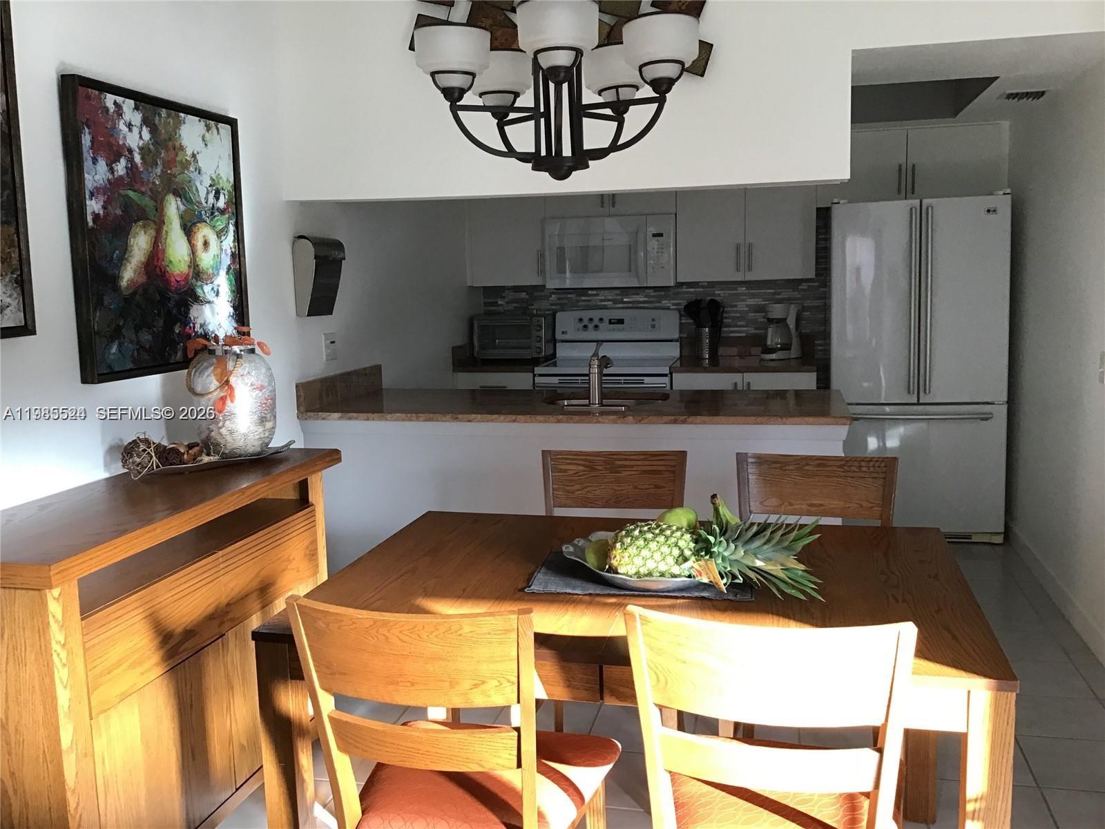 A dining area with a wooden table and chairs sits in front of an open kitchen — 609 Waterside Dr # 609, Hypoluxo FL 33462, HYPOLUXO, FL