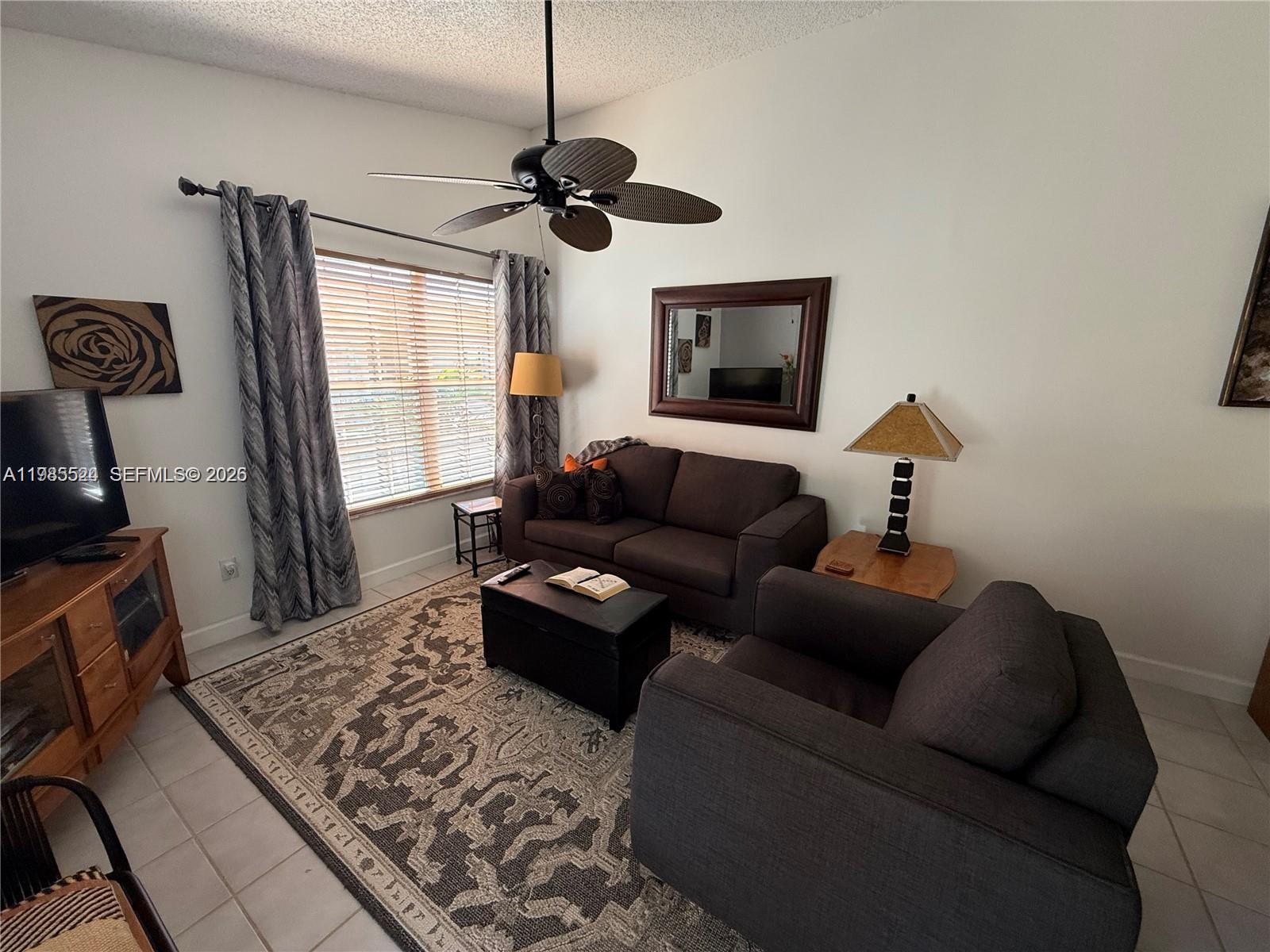 A living room features a dark sofa, armchair, patterned rug, and a ceiling fan — 609 Waterside Dr # 609, Hypoluxo FL 33462, HYPOLUXO, FL