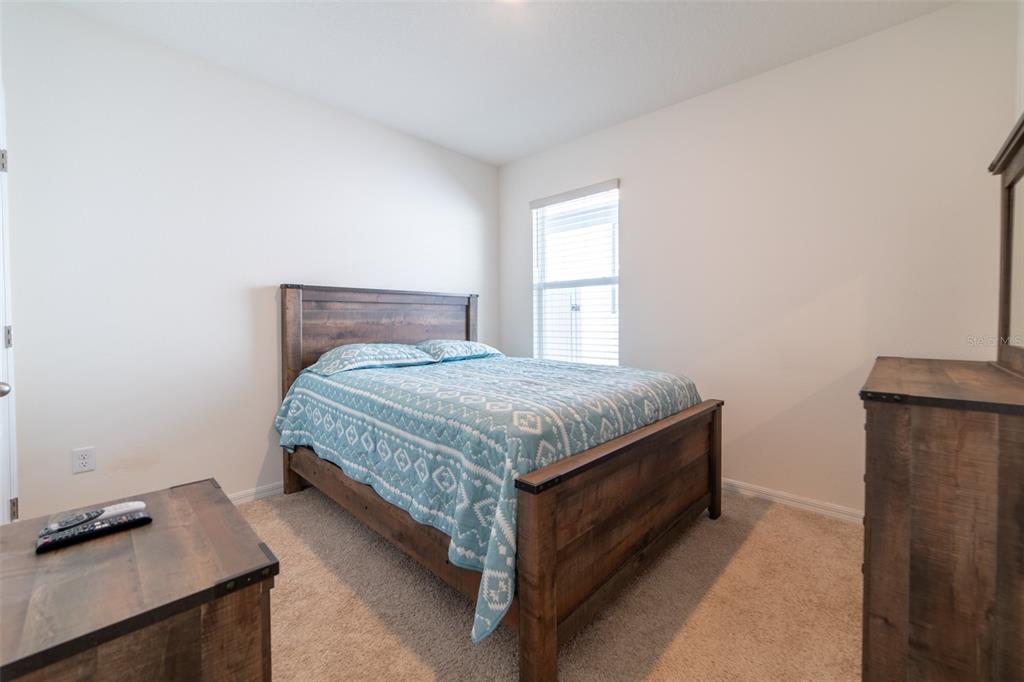 A bedroom features a wooden bed frame, a blue patterned quilt, and a dresser — 2684 MAGNOLIA AVENUE, DAVENPORT, FL