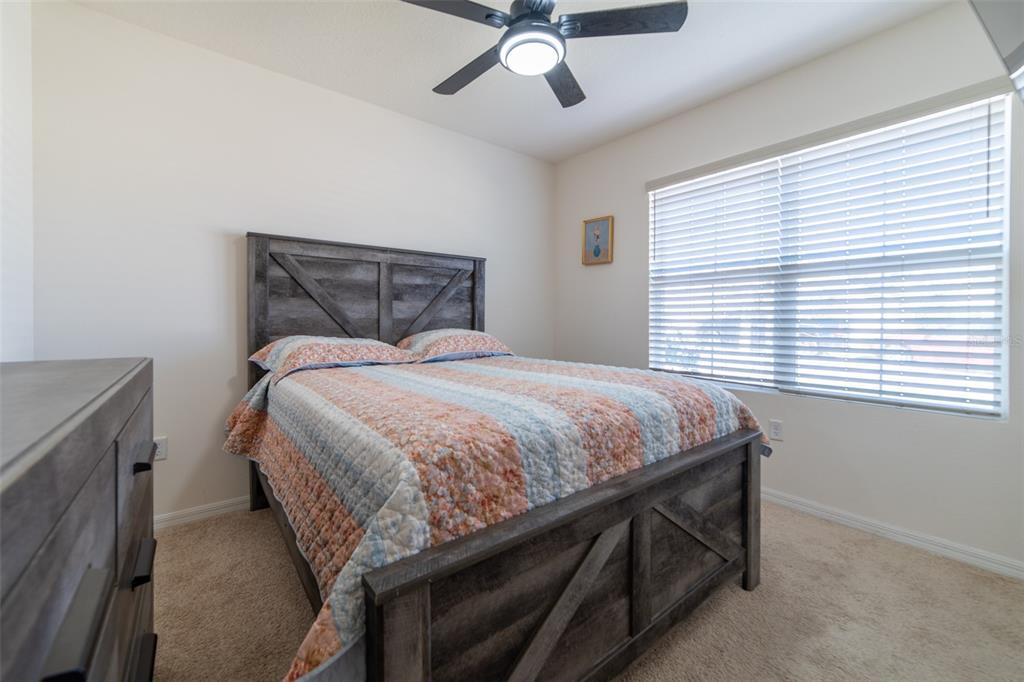 A bedroom features a rustic wooden bed frame, a ceiling fan, and a large window — 2684 MAGNOLIA AVENUE, DAVENPORT, FL