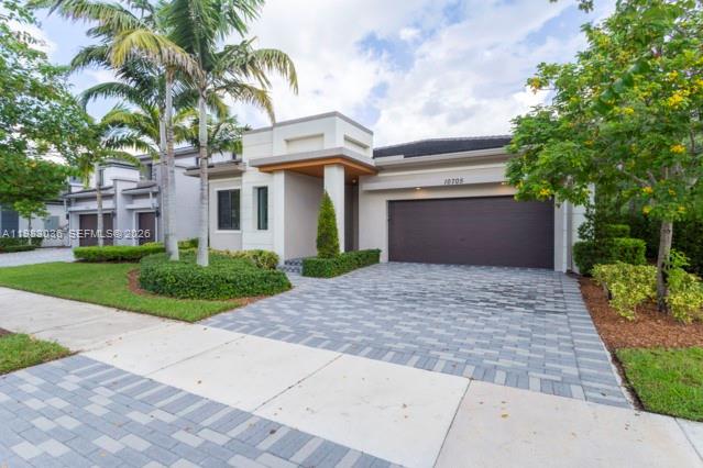 A modern one-story house features a paved driveway, a two-car garage, and palm trees — 10705 Pacifica Way, Parkland FL 33076, PARKLAND, FL
