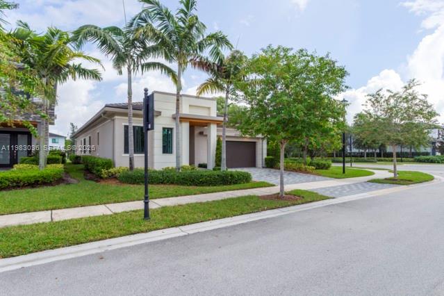 A modern single-story house with a paved driveway, palm trees, and a dark garage door — 10705 Pacifica Way, Parkland FL 33076, PARKLAND, FL
