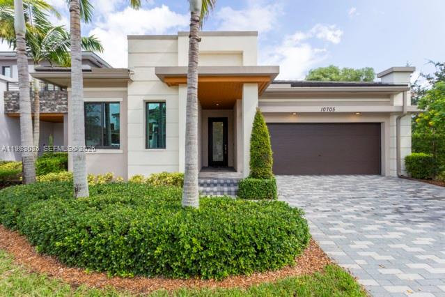 A modern single-story house features a paved driveway, a two-car garage, and palm trees — 10705 Pacifica Way, Parkland FL 33076, PARKLAND, FL