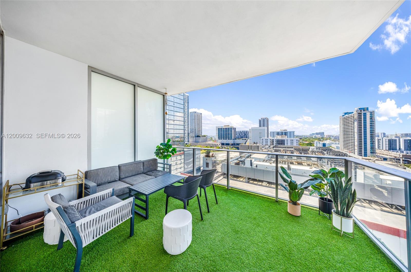 A balcony with artificial grass, outdoor furniture, and a view of a city skyline — 851 NE 1st Ave # 1408, Miami FL 33132, MIAMI, FL