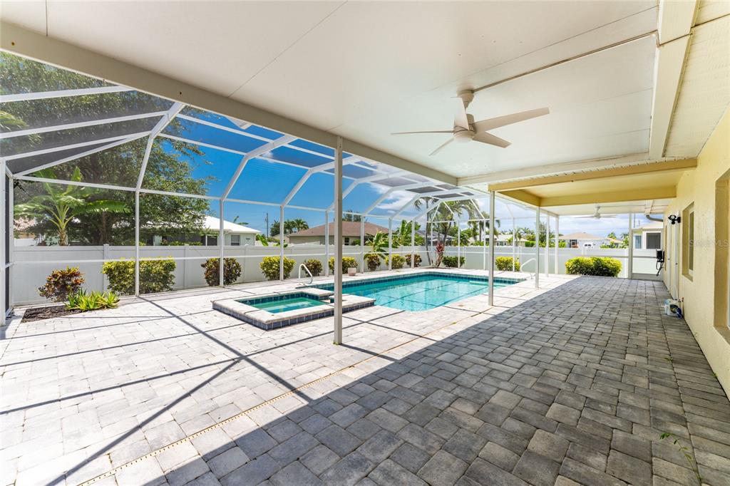 A covered patio with pavers overlooks a swimming pool and spa inside a screened enclosure — 3310 SW 26TH AVENUE, CAPE CORAL, FL