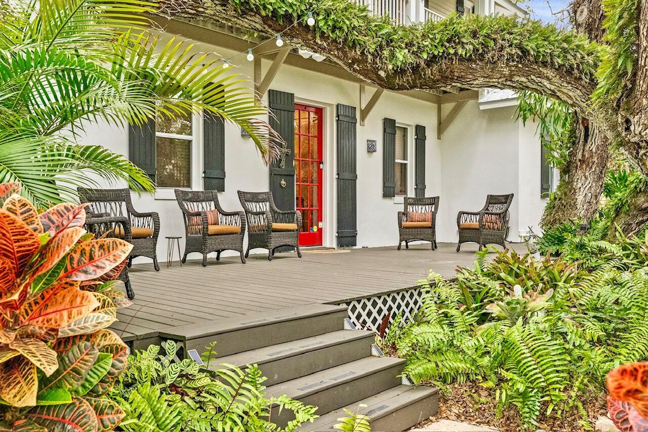 A wooden deck with wicker chairs leads to a house with a red front door — 3628 Rio Vista Boulevard, Vero Beach FL 32963, VERO BEACH, FL