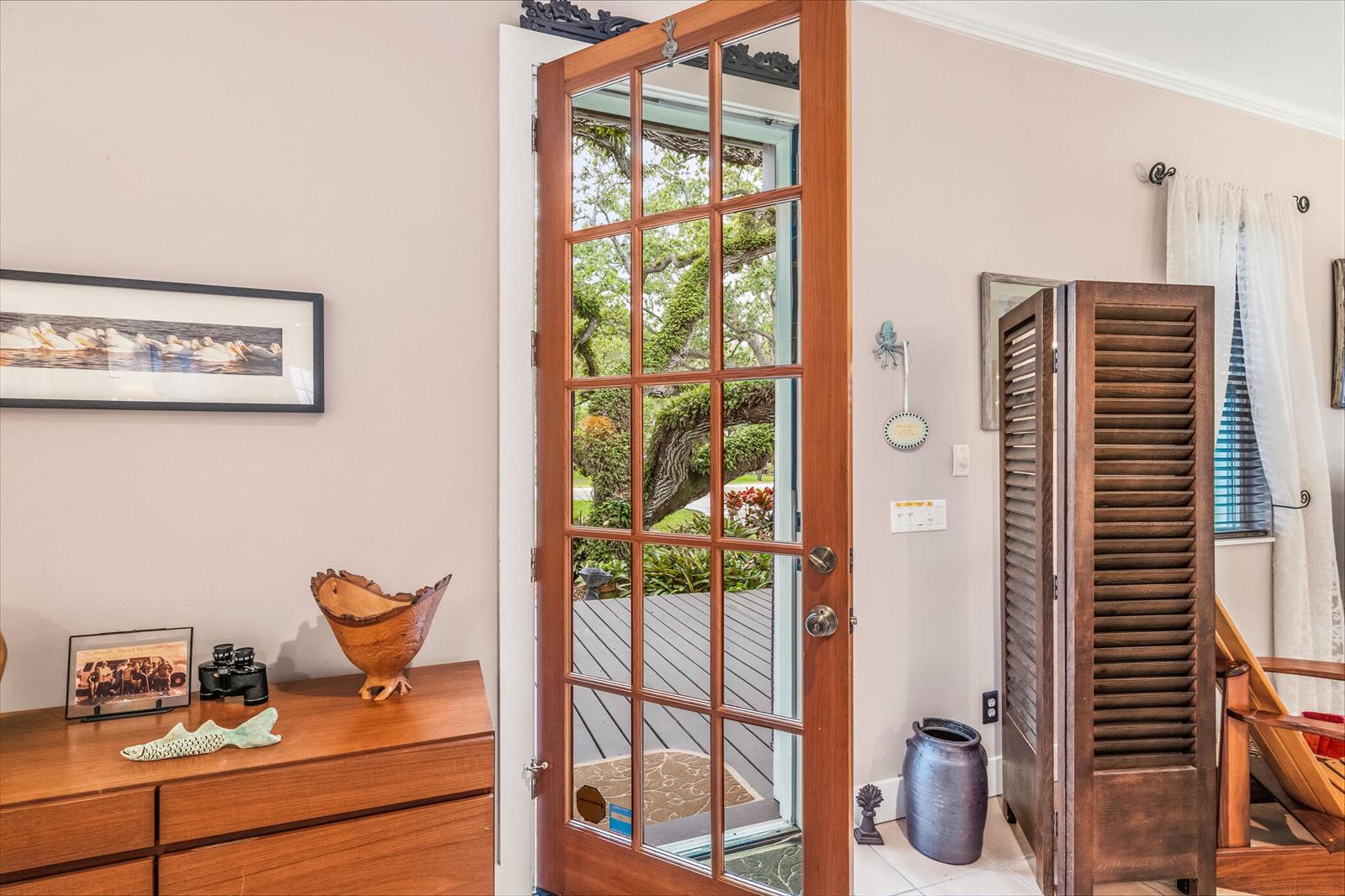 A wooden door with glass panes opens to a deck and trees in this room — 3628 Rio Vista Boulevard, Vero Beach FL 32963, VERO BEACH, FL
