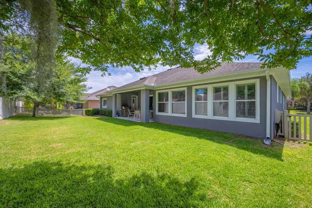A backyard view of a gray house with a covered patio and large windows — 1210 LOREA LANE, BRANDON, FL