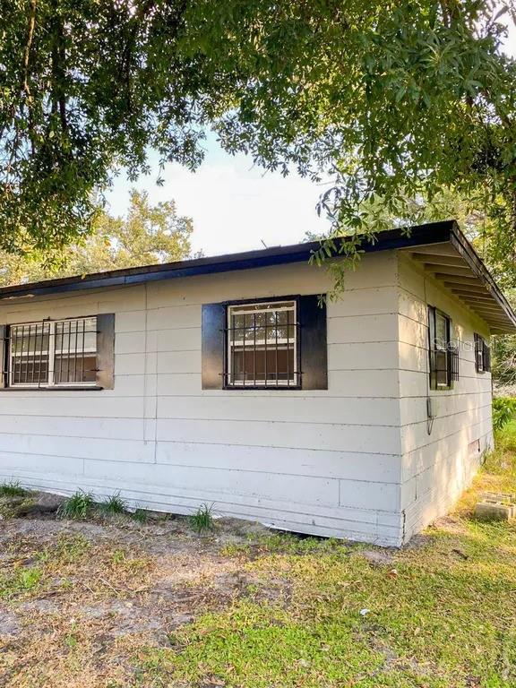The exterior of a white, single-story house features dark shutters and security bars on the windows — 4638 AMERICA, ORLANDO, FL
