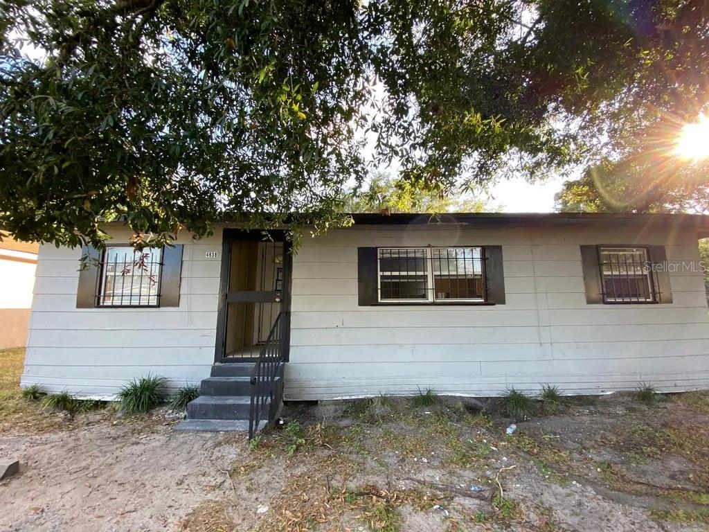 A single-story house with light gray siding, dark shutters, and security bars on the windows — 4638 AMERICA, ORLANDO, FL