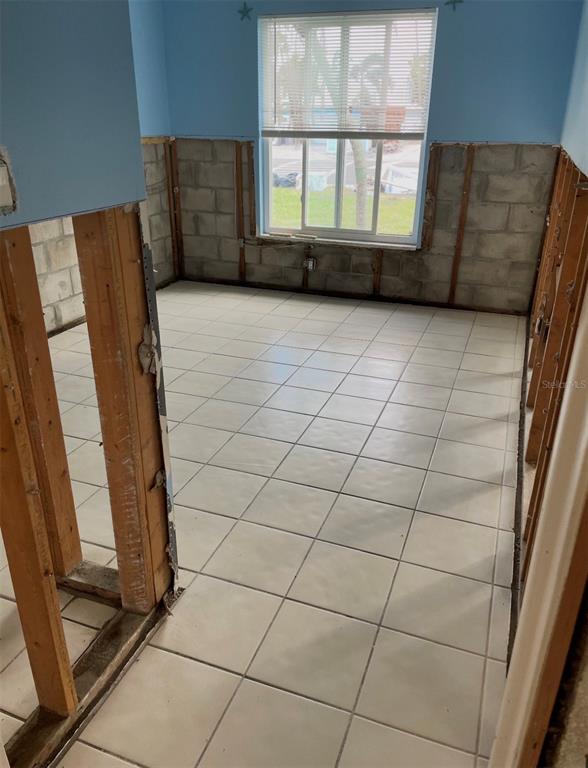 An unfinished room features exposed wall studs, concrete block walls, and white floor tiles — 16101 GULF BOULEVARD, REDINGTON BEACH, FL