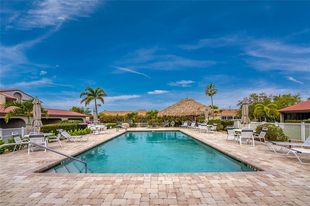 A rectangular swimming pool with a tiki hut and lounge chairs on a paved deck — 2601 W MARION AVENUE UNIT 42A, PUNTA GORDA, FL