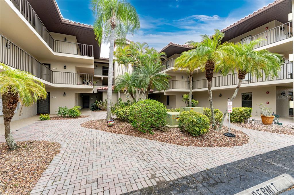 An exterior view of a multi-story apartment complex courtyard with palm trees and paved walkways — 2601 W MARION AVENUE UNIT 42A, PUNTA GORDA, FL
