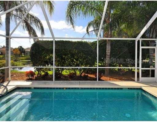 A screened-in swimming pool overlooks a pond and lush landscaping — 5506 MODENA PLACE, SARASOTA, FL