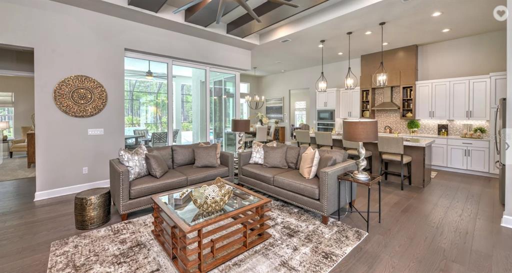 An open-concept living room and kitchen featuring gray sofas, a wood coffee table, and cabinetry — 17 KENSINGTON STREET, ORMOND BEACH, FL