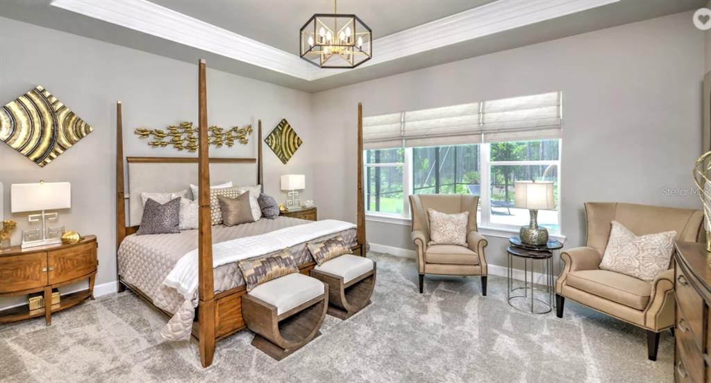A bedroom with a four-poster bed, two armchairs, and a large window overlooking a pool — 17 KENSINGTON STREET, ORMOND BEACH, FL