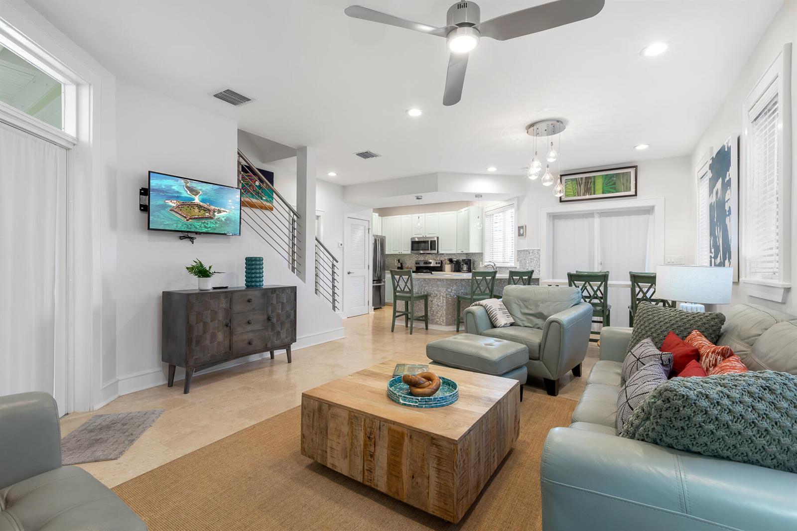 An open-concept living room features a light blue sofa, wooden coffee table, and kitchen area — 1011 Simonton Street # 1, Key West FL 33040, KEY WEST, FL