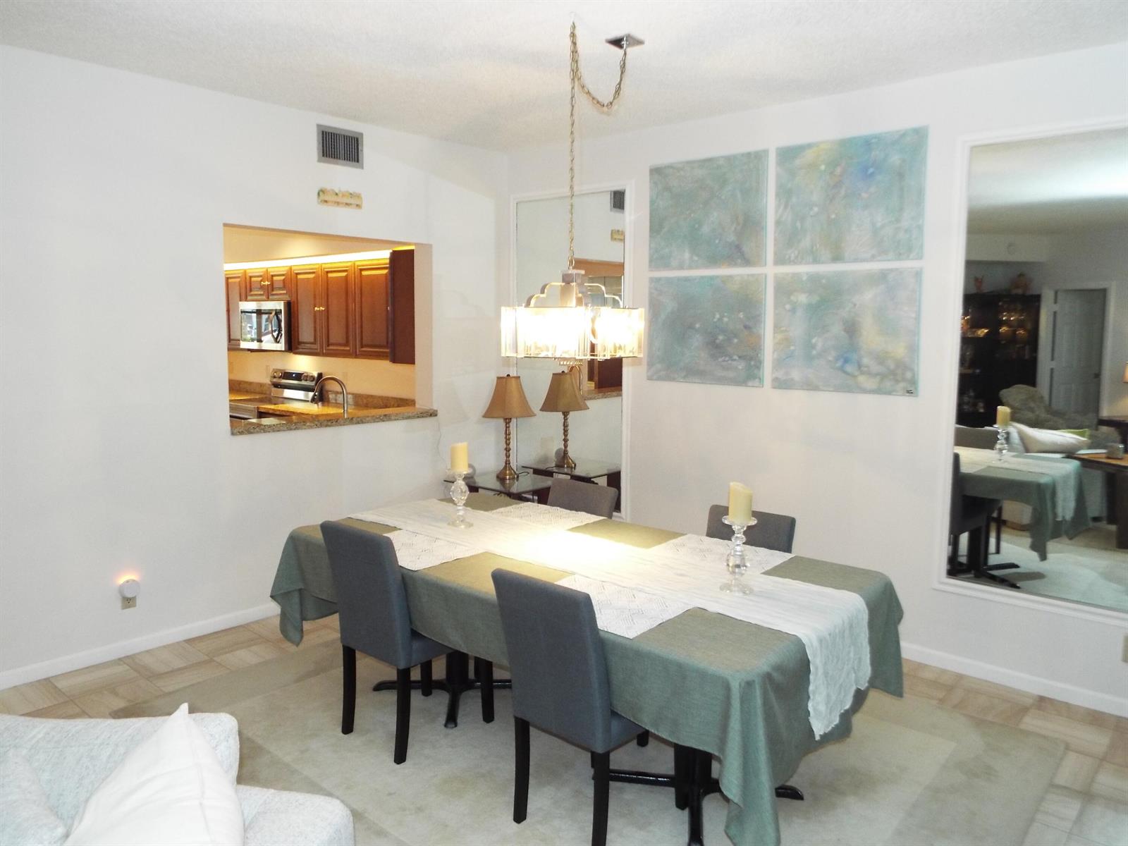 A dining room features a table with gray chairs, a chandelier, and wall-mounted artwork — 4128 W Palm Aire Drive # 281b, Pompano Beach FL 33069, POMPANO BEACH, FL
