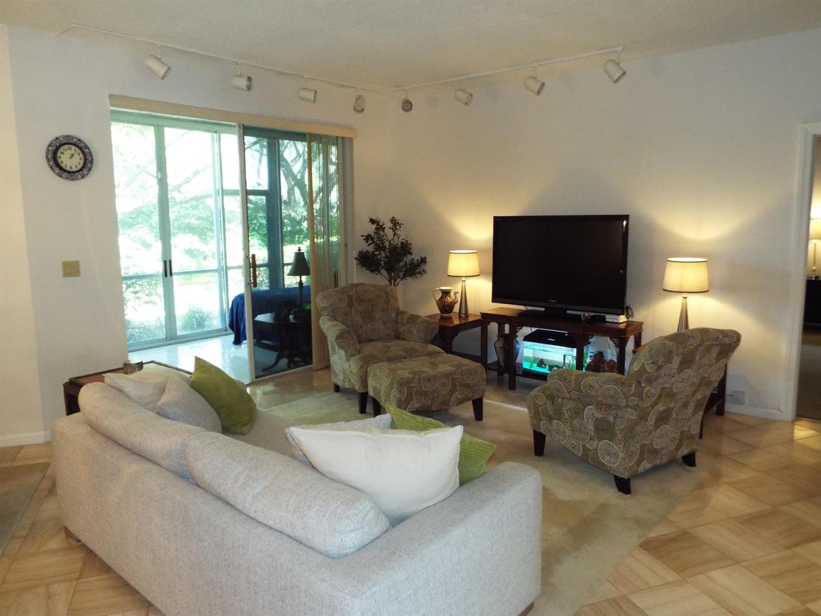 A living room features a sofa, two patterned armchairs, a television, and sliding glass doors — 4128 W Palm Aire Drive # 281b, Pompano Beach FL 33069, POMPANO BEACH, FL
