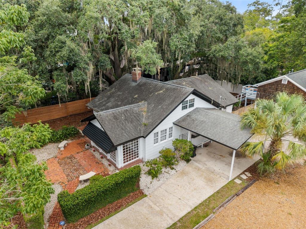 An aerial view of a white house with a black roof, carport, and brick patio — 16 NW 20TH TERRACE, GAINESVILLE, FL