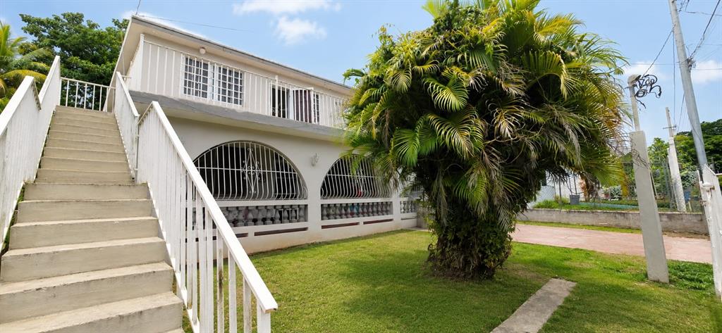 A two-story house with an exterior staircase and arched windows with security bars — calle 10 Int. PARCELAS VANSCOY, BAYAMON, PR