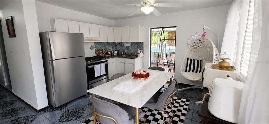 A kitchen and dining area features white cabinets, stainless steel appliances, and a hanging chair — calle 10 Int. PARCELAS VANSCOY, BAYAMON, PR