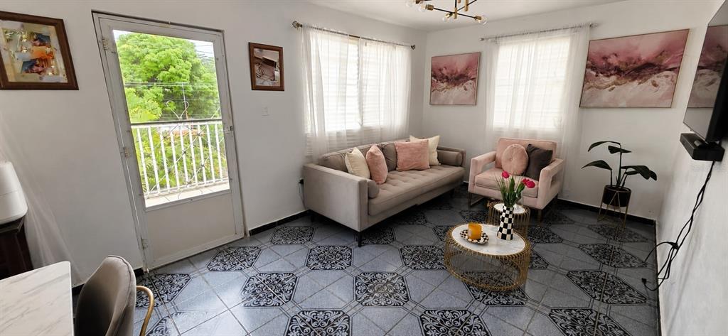 A living room features a grey sofa, a pink armchair, patterned tile floors, and a balcony — calle 10 Int. PARCELAS VANSCOY, BAYAMON, PR