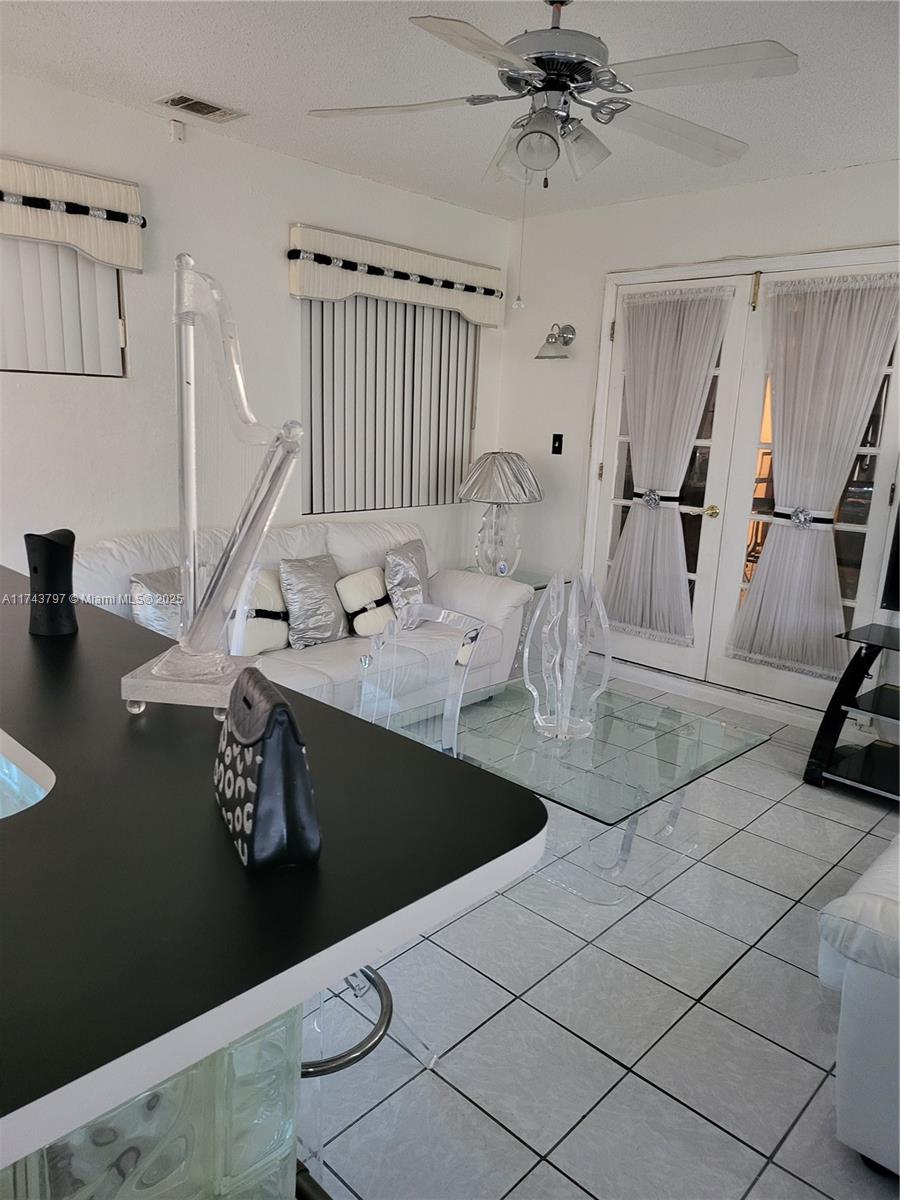A living room features white furniture, a glass coffee table, and a black kitchen counter — 6771 NW 199th Ter, Hialeah FL 33015, HIALEAH, FL