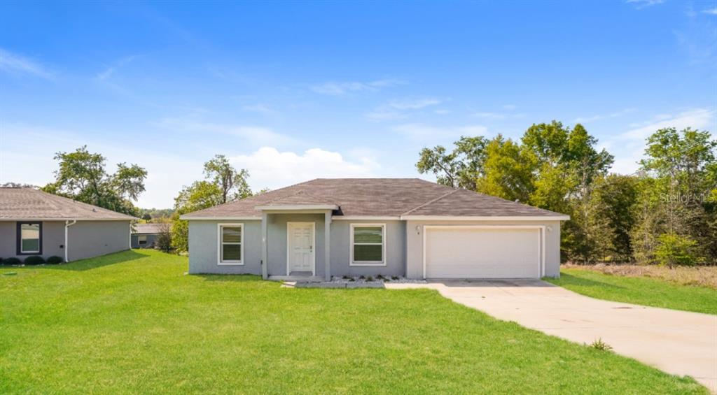 A single-story house with a gray exterior, a two-car garage, and a concrete driveway — 2656 W CASTANIA DRIVE, DUNNELLON, FL