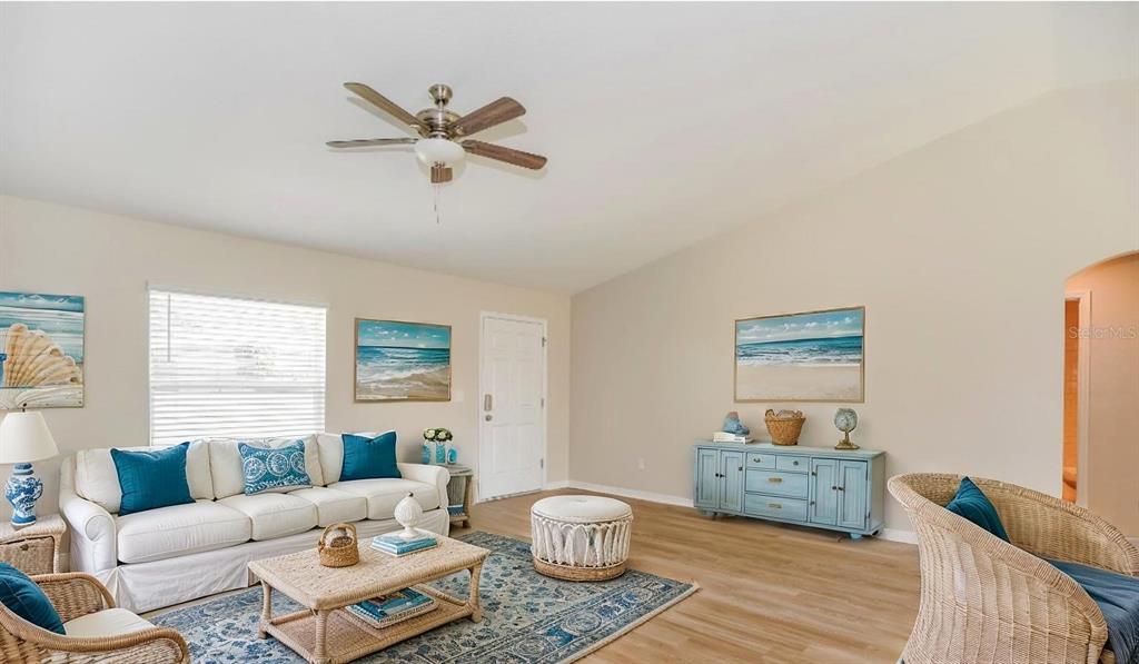 A living room features a white sofa, wicker furniture, a blue area rug, and light flooring — 2656 W CASTANIA DRIVE, DUNNELLON, FL