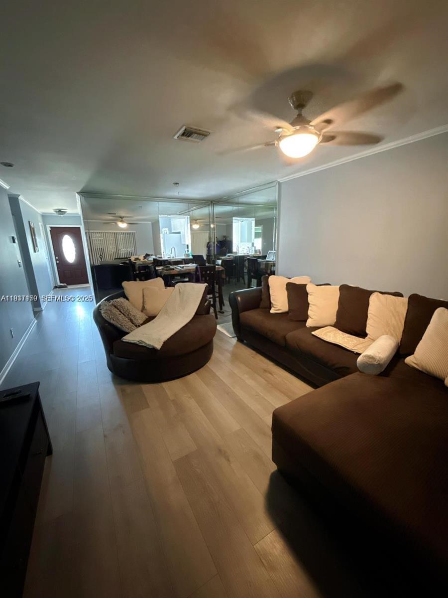A living room features brown sofas, light wood flooring, and a mirrored wall — 6720 Moonlit Dr, Delray Beach FL 33446, DELRAY BEACH, FL