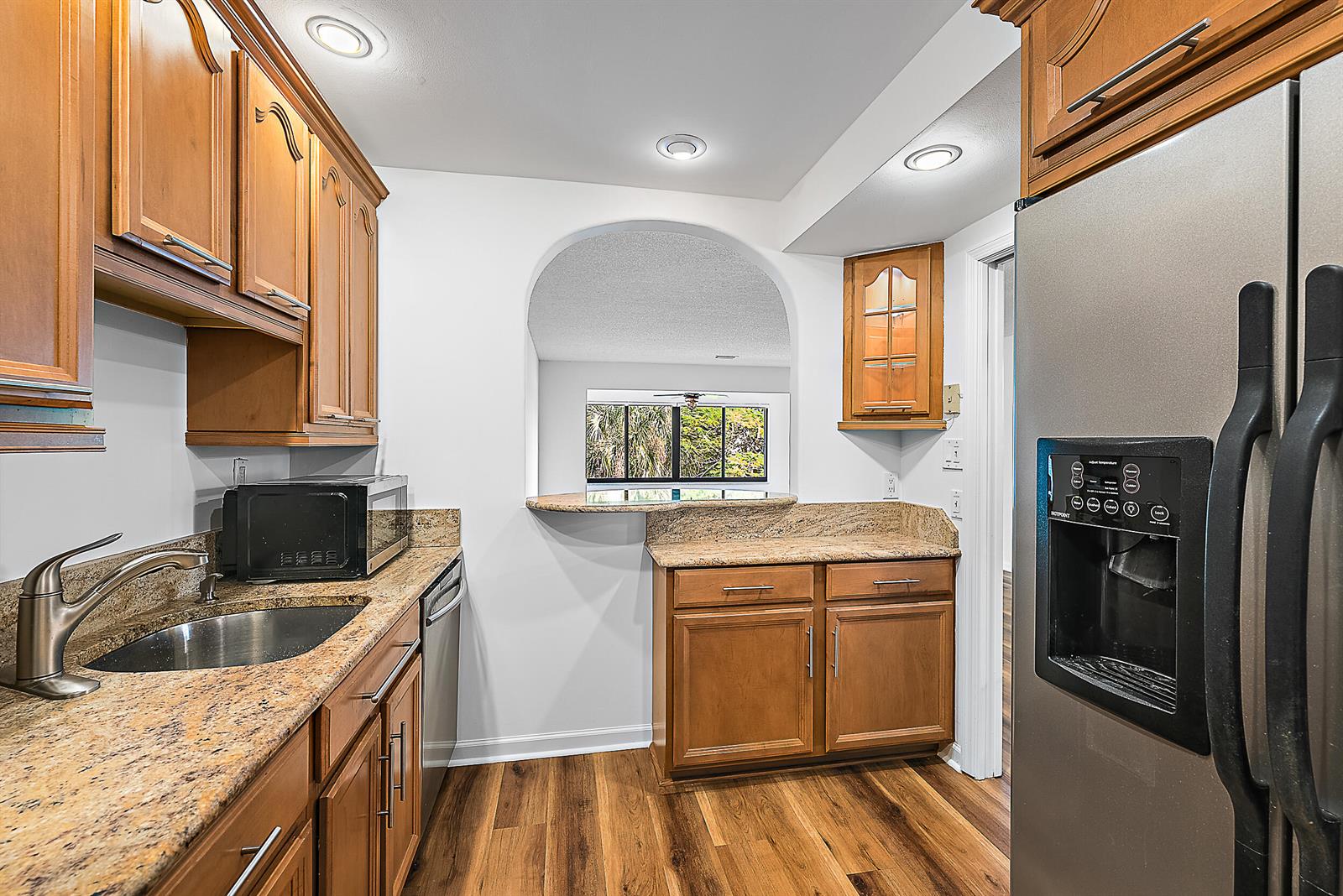 An empty room features wood-look flooring, white walls, large windows, and a stained-glass ceiling fan — 300 N Highway A1a # 303g, Jupiter FL 33477, JUPITER, FL