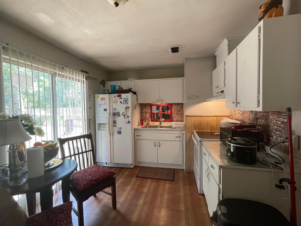 A kitchen features white cabinets, a refrigerator, a dining table, and a sliding glass door — 263 ROSS ROAD, TALLAHASSEE, FL