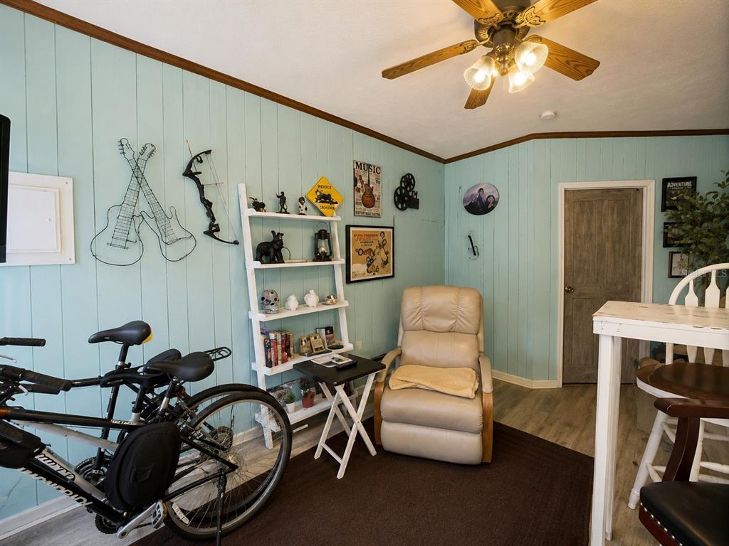 A room with light blue wood-paneled walls, a recliner, a bookshelf, and a bicycle — 263 ROSS ROAD, TALLAHASSEE, FL