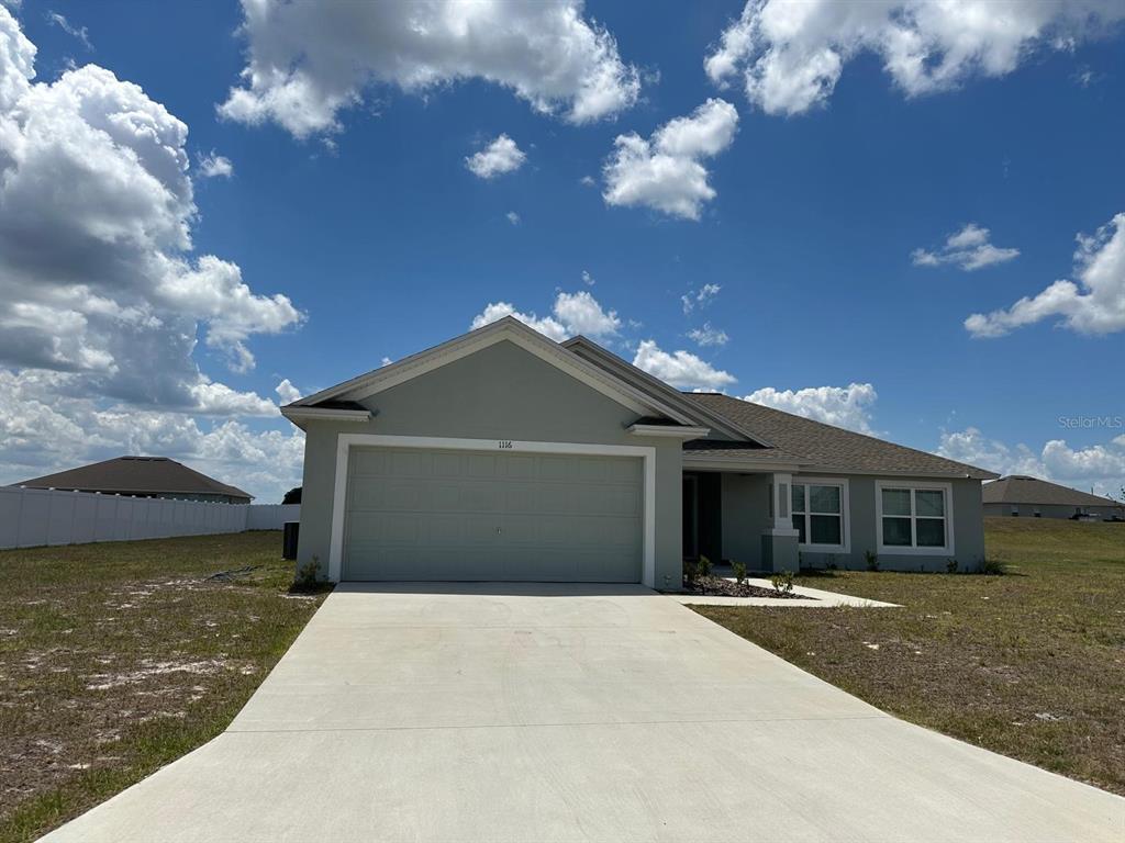 A single-story house with a light green exterior, a two-car garage, and a concrete driveway — 1116 CALOOSA RIDGE WAY, BABSON PARK, FL