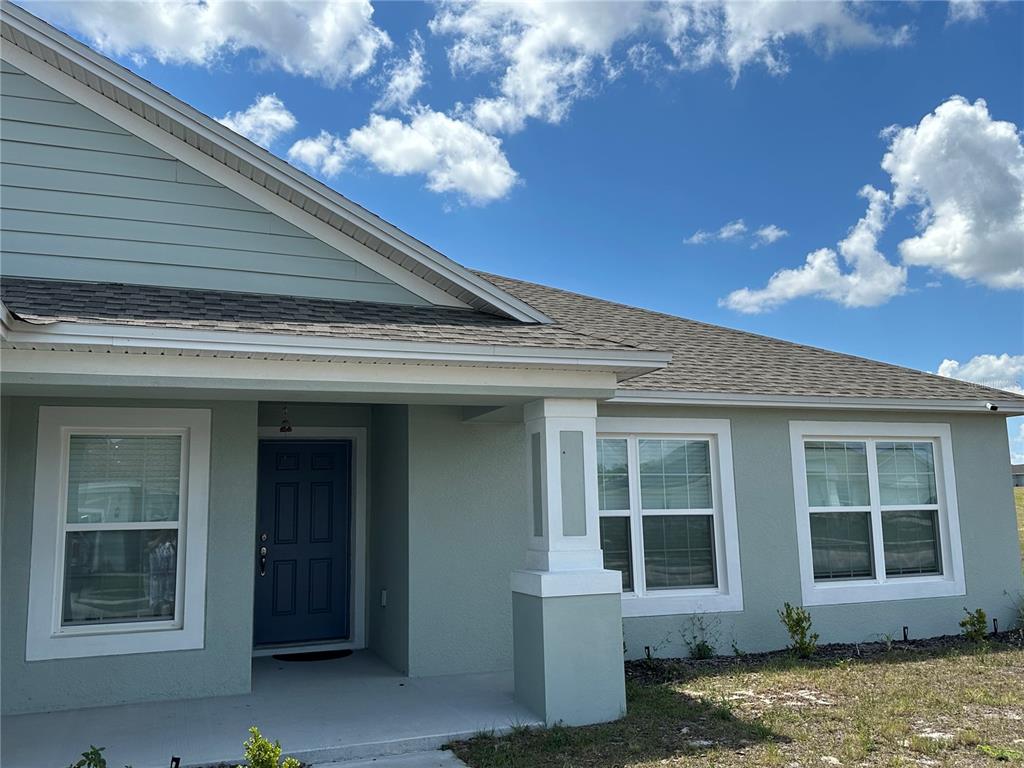 The exterior of a light green house features a blue front door and white trim — 1116 CALOOSA RIDGE WAY, BABSON PARK, FL
