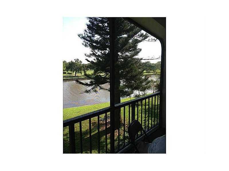 A view of a lake and a large tree from a screened-in balcony — 3760 Inverrary Drive # 2h, Lauderhill FL 33319, LAUDERHILL, FL