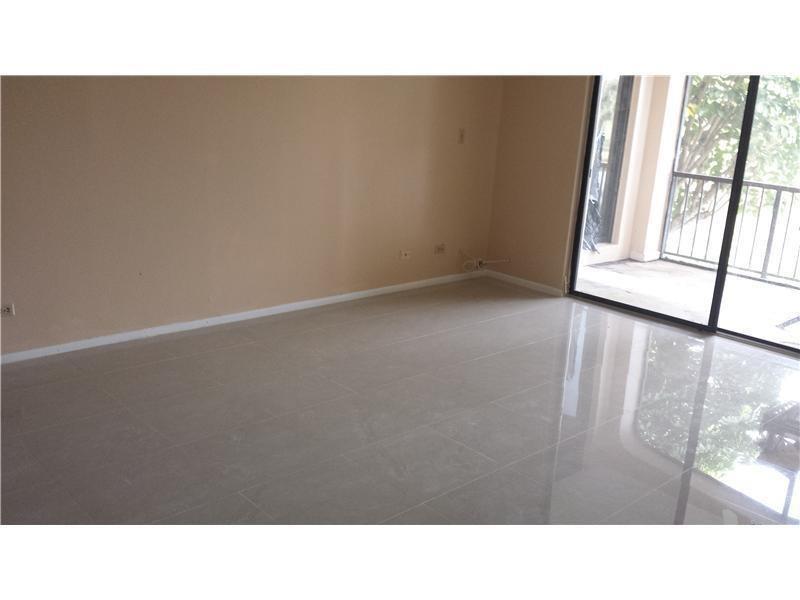 An empty room features light-colored tile flooring, beige walls, and a sliding glass door — 3760 Inverrary Drive # 2h, Lauderhill FL 33319, LAUDERHILL, FL