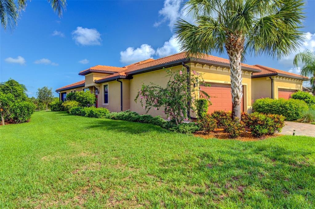 A single-story house with a tile roof, tan stucco walls, and a palm tree — 12232 MARSH POINTE ROAD, SARASOTA, FL