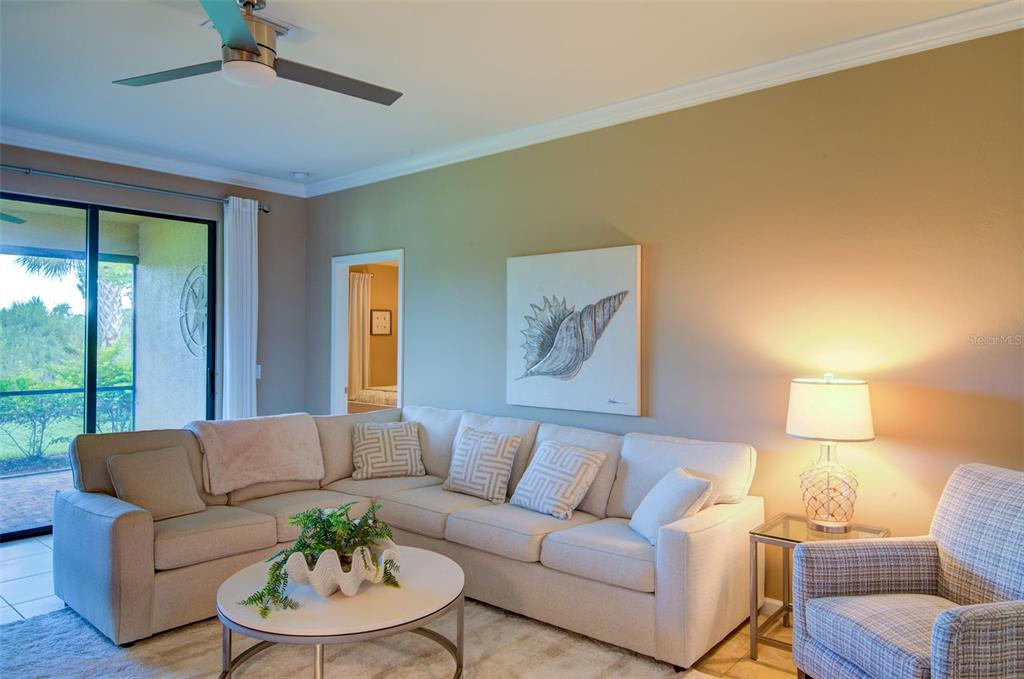 A living room features a beige sectional sofa, a round coffee table, and a seashell painting — 12232 MARSH POINTE ROAD, SARASOTA, FL