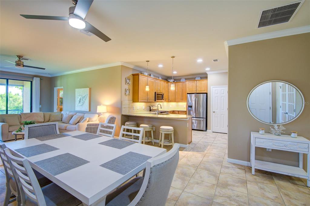 An open-concept dining area and kitchen feature light tile flooring and wooden cabinetry — 12232 MARSH POINTE ROAD, SARASOTA, FL