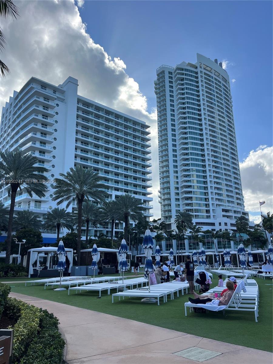 A view of two tall white residential buildings overlooking a pool deck with lounge chairs — 4391 Collins Ave # 419, Miami Beach FL 33140, MIAMI BEACH, FL