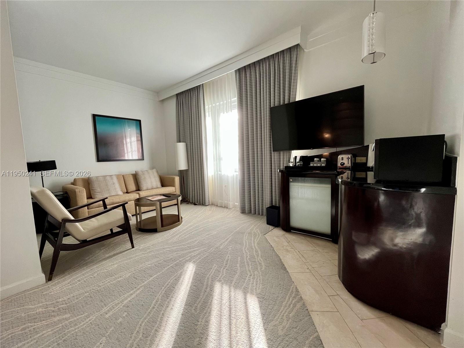 A living room features a sofa, an armchair, a television, and a patterned area rug — 4391 Collins Ave # 419, Miami Beach FL 33140, MIAMI BEACH, FL