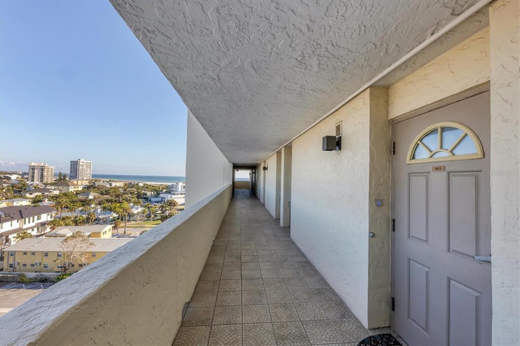 An outdoor walkway with tiled flooring leads to a door numbered 903 overlooking the ocean — 20 WHISPERING SANDS DRIVE UNIT 903, SARASOTA, FL