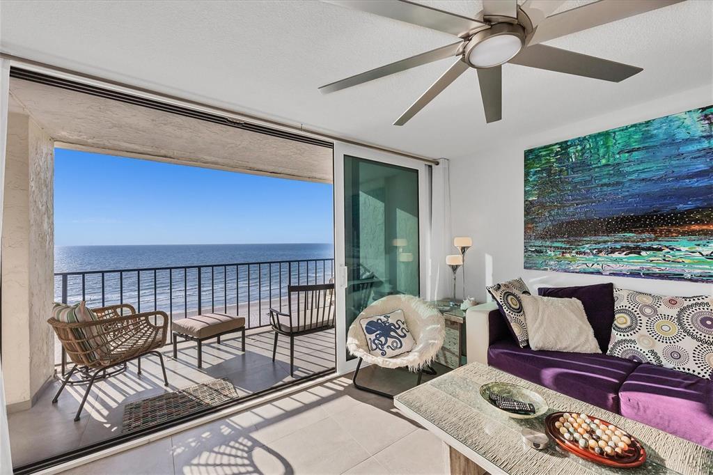 A living room with a purple sofa and a balcony overlooking the ocean — 20 WHISPERING SANDS DRIVE UNIT 903, SARASOTA, FL