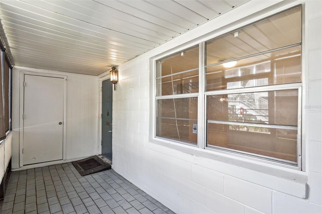 A covered porch with a tiled floor, a white door, and a large window — 700 E AIRPORT BLVD UNIT I2, SANFORD, FL