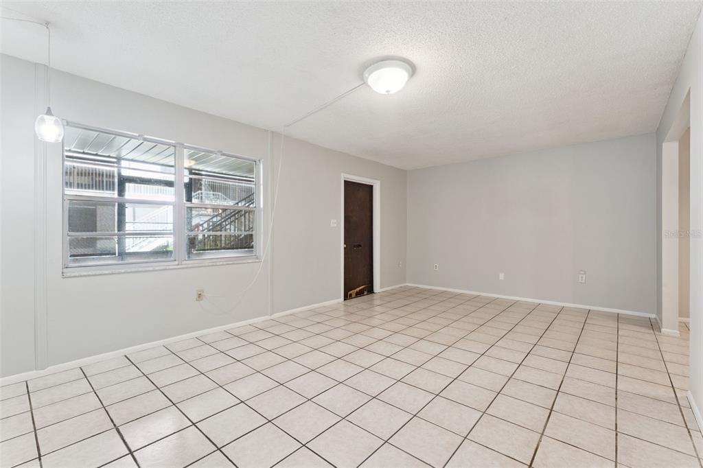 An empty room with light-colored tile flooring, gray walls, a ceiling light, and a window — 700 E AIRPORT BLVD UNIT I2, SANFORD, FL