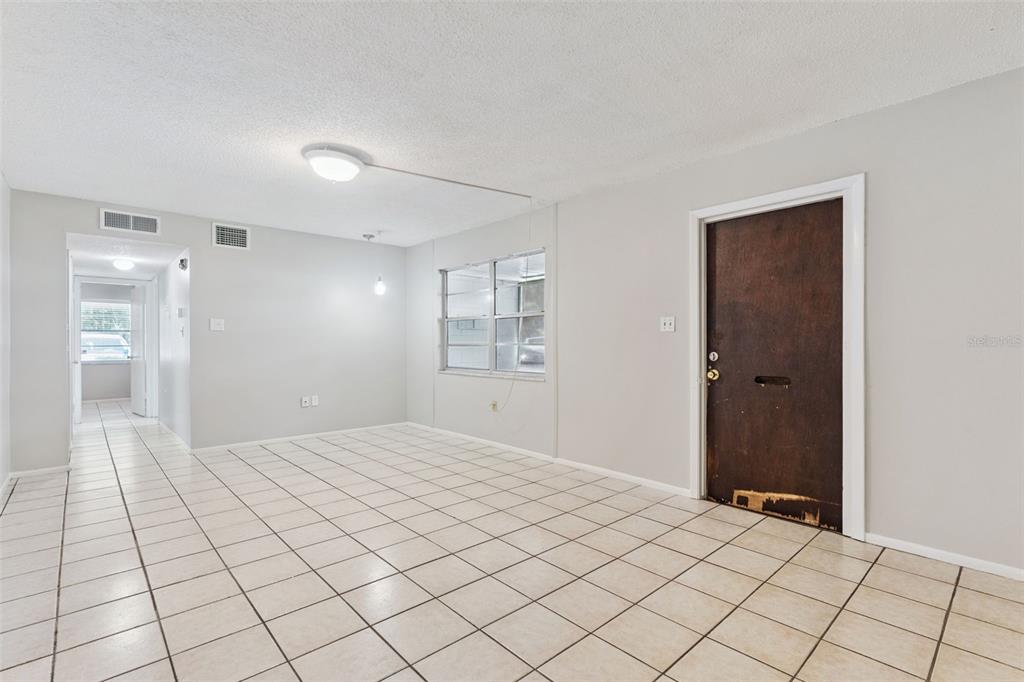 An interior view of a room with white walls, tiled flooring, and a dark wooden door — 700 E AIRPORT BLVD UNIT I2, SANFORD, FL