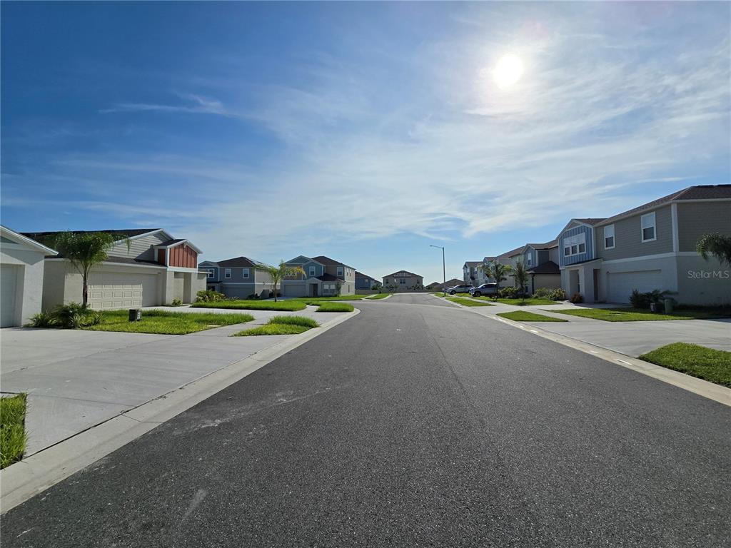 A street view of a suburban neighborhood with modern two-story houses under a sunny sky — 2441 OAKWOOD LANE, DAVENPORT, FL