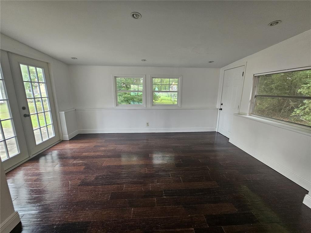 A sunroom features dark wood flooring, white walls with wainscoting, recessed lighting, and glass doors — 26 LAKE COURT LOOP, OCALA, FL